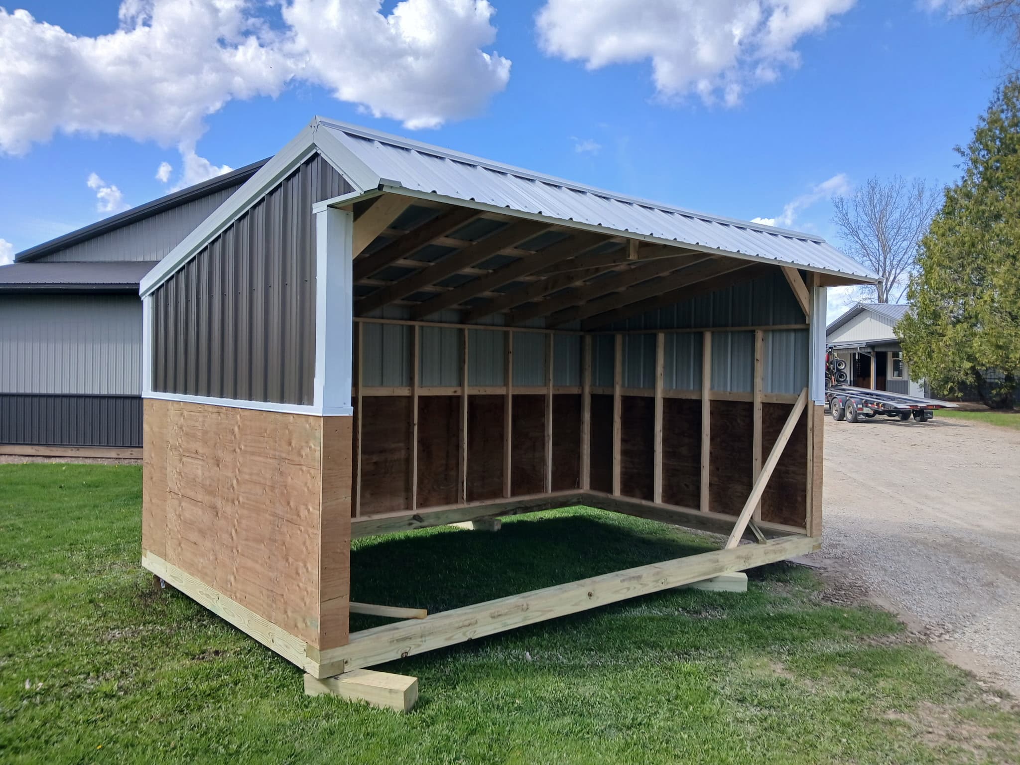 Charcoal and white custom horse shelter with an open front and metal roof.